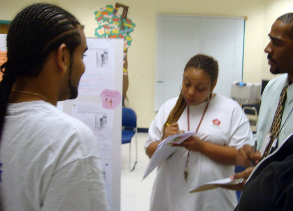 Three young black college students at a poster presentation of a graduate class.