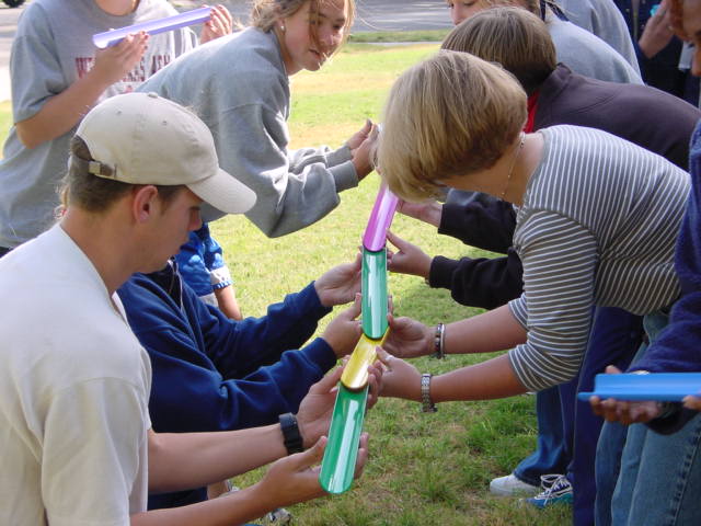 Students holding tubes joined to allow a ball to roll down it (part of a class activity).